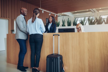 Picture of Two smiling guests checking in at a hotel reception