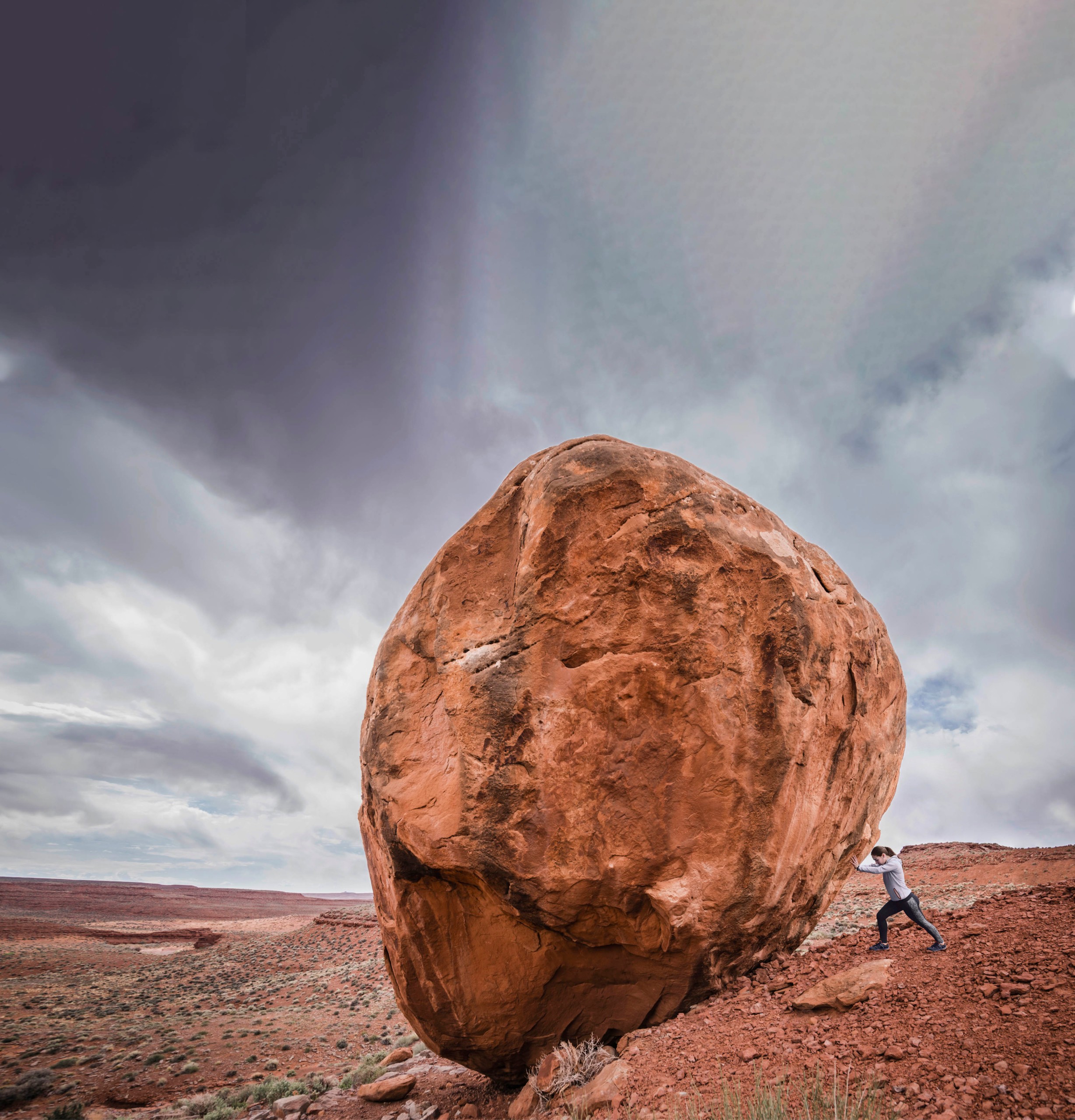 Caucasian man pushing boulder in desert landscape