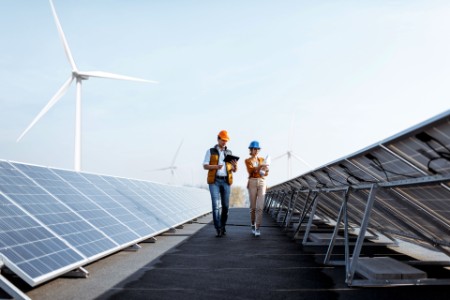 View on rooftop solar power plant with engineers examining photovoltaic panels