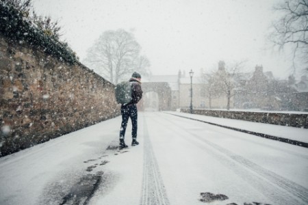 Man struggling to walk in the snow in a city