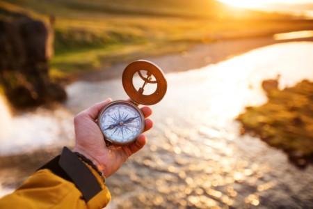A person holding a compass over a river