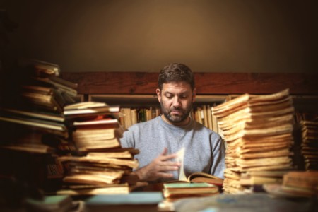 Man reading and sorting books and documents in library archive