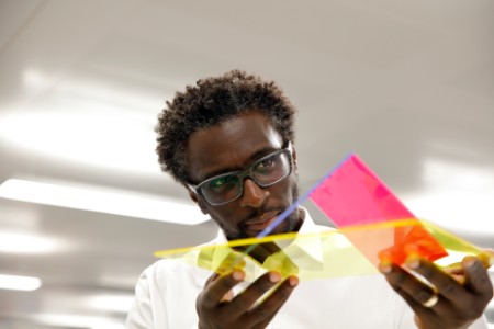 Man with glasses looking at yellow and pink object 