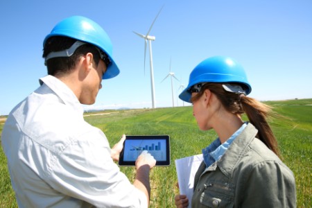 Man and Woman looking at a graph in front of a wind turbine