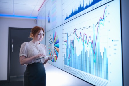 Businesswoman studying graphs on screen with digital tablet