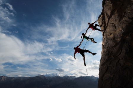 Rock climbers helping one from falling