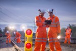 Railway maintenance workers using digital tablet at night