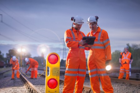 Railway maintenance workers using digital tablet at night