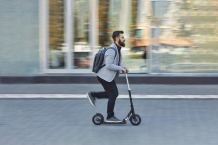 Businessman riding scooter along office building