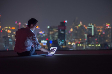 Man with laptop overlooking skyline