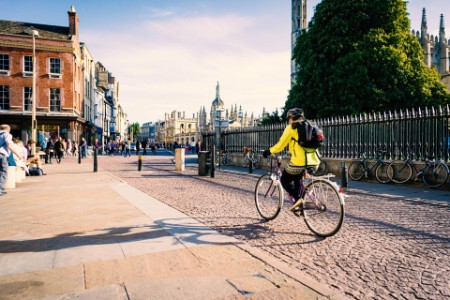Cyclist riding on a cobblestone street in Cambridge