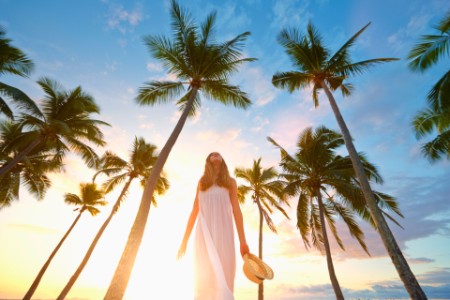 Lady wearing white dress walking by palm trees