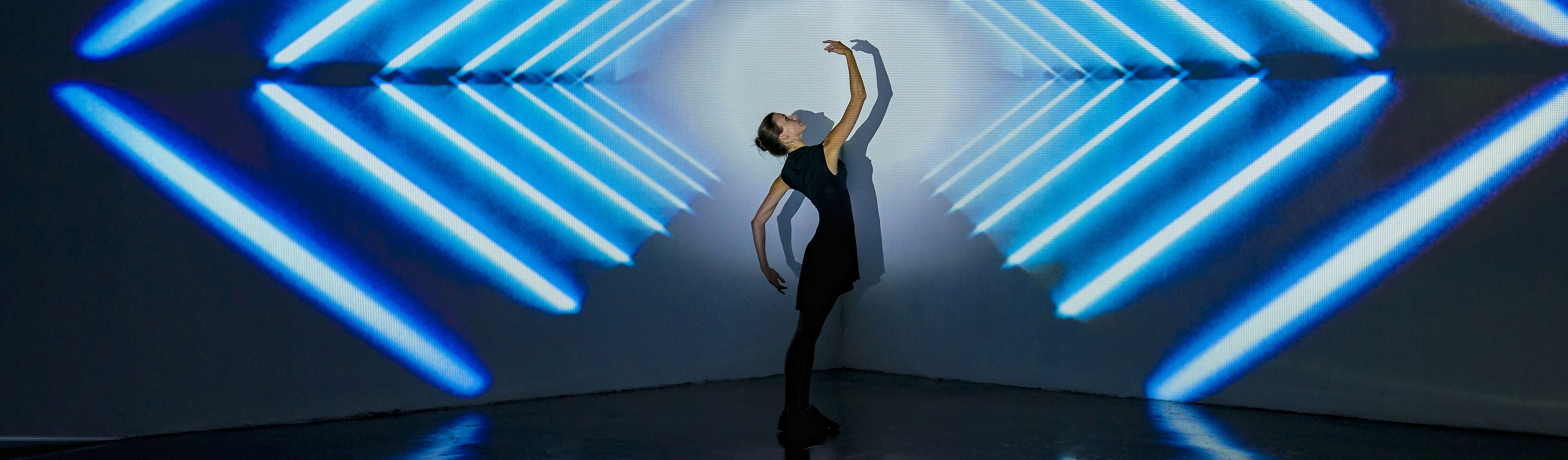 Girl dancing in a studio with graphic patterns projected onto wall behind her