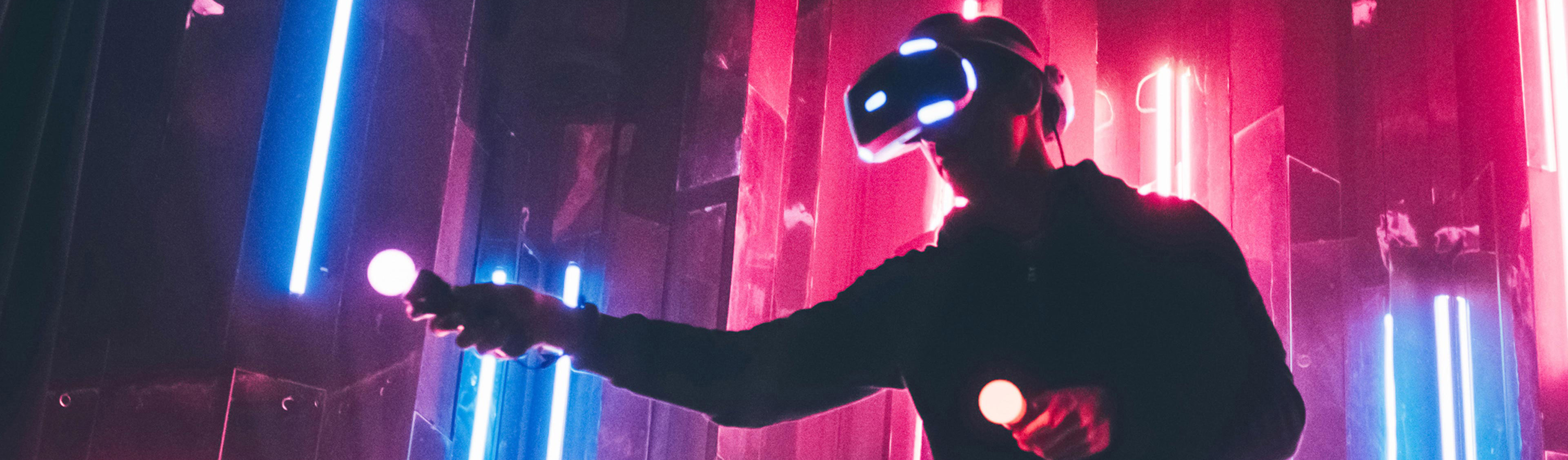 Man wearing VR headset in dark space with neon light lamps