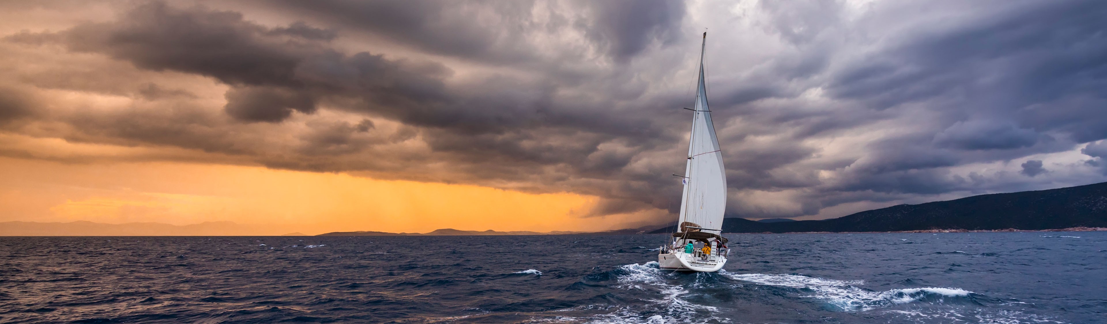 Yacht with white sails on a background of storm clouds
