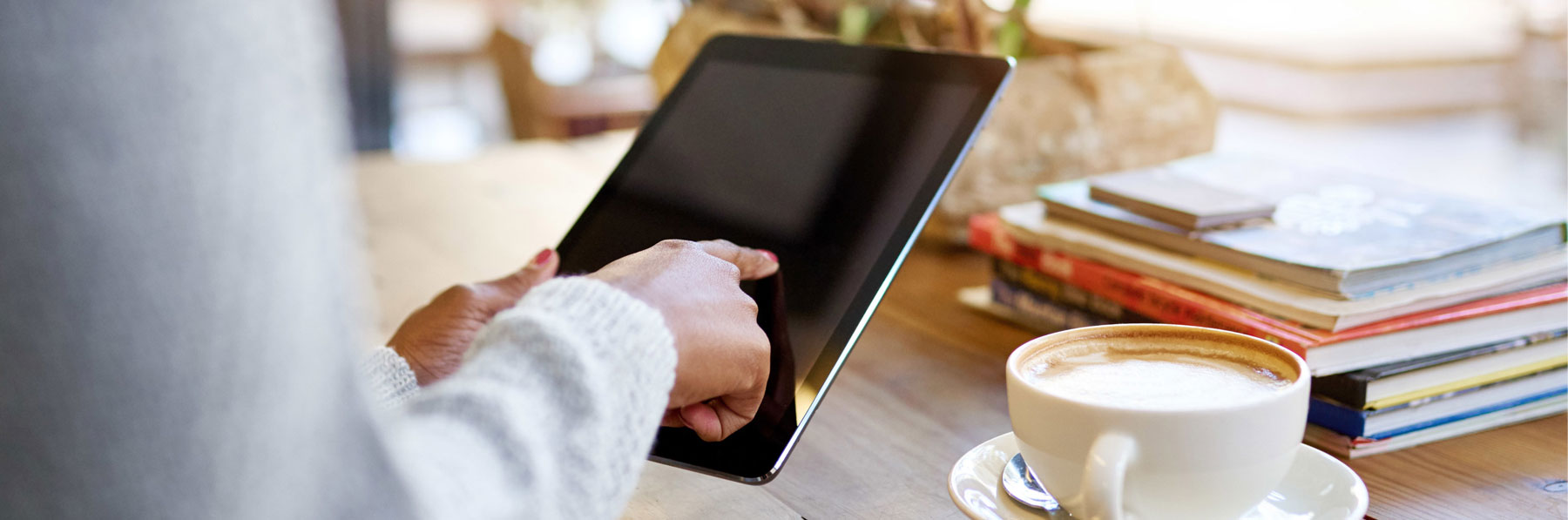 Closeup of a young woman sitting at a table in a cafe using a digital tablet