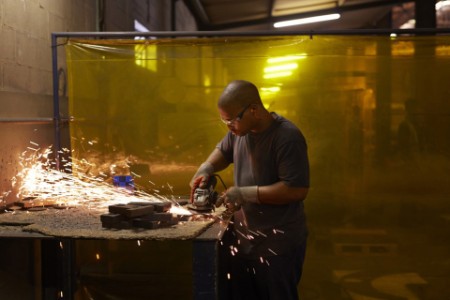 Man grinding metal in factory