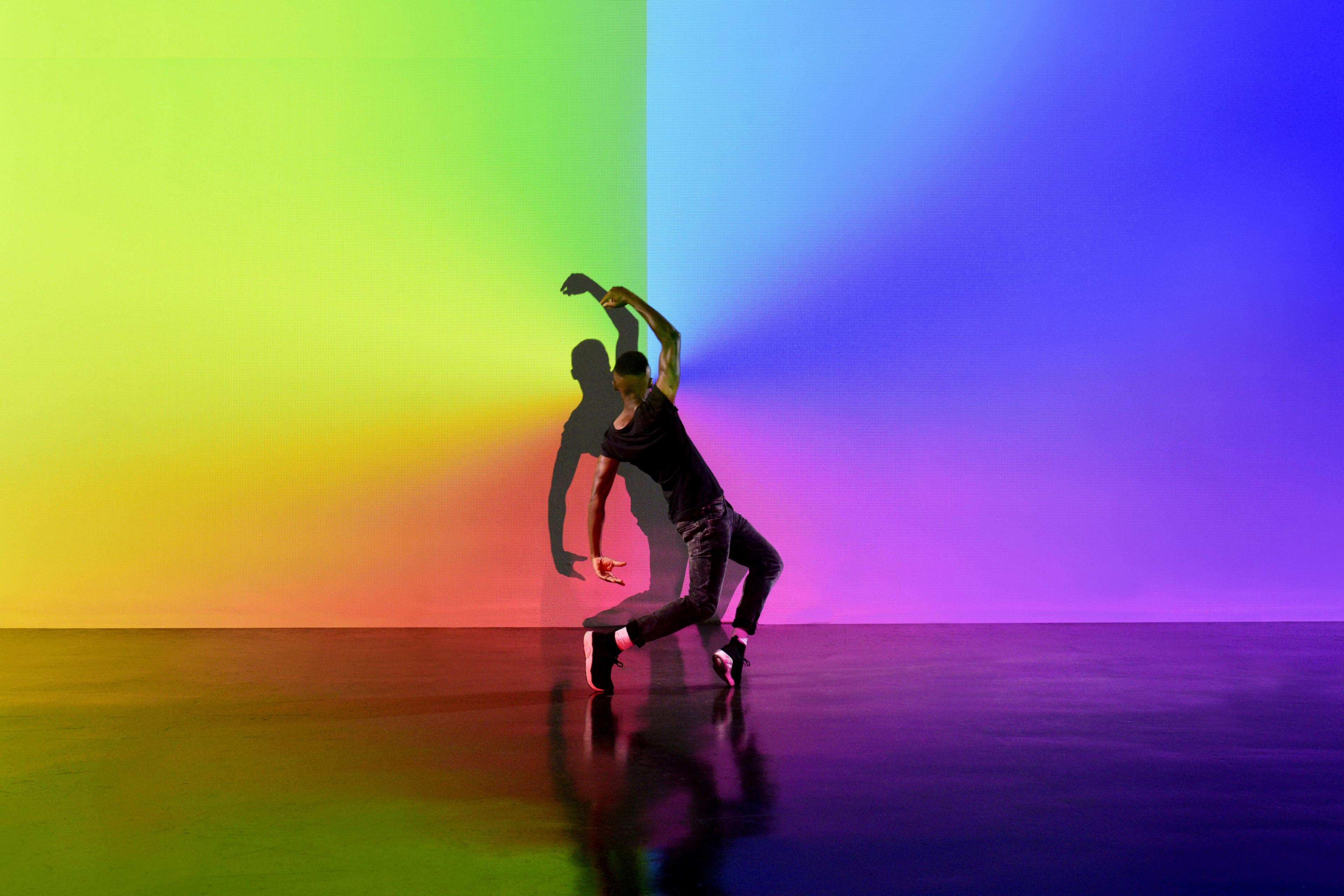 Man dancing in an abstract space with lots of colors behind him