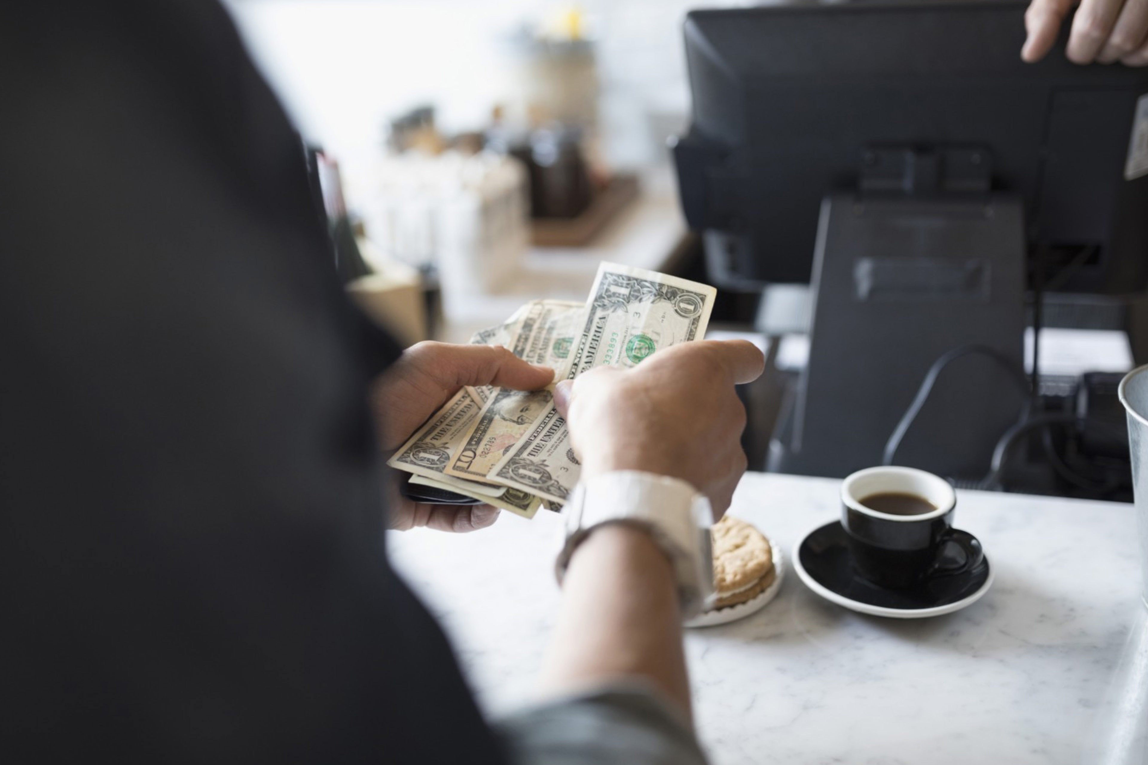 Man holding dollars in hand at a coffee shop