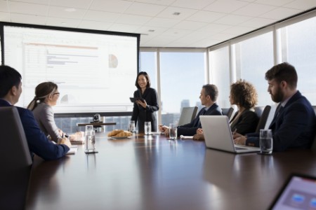 Businesswoman with digital tablet leading presentation at projection screen in conference room meeting