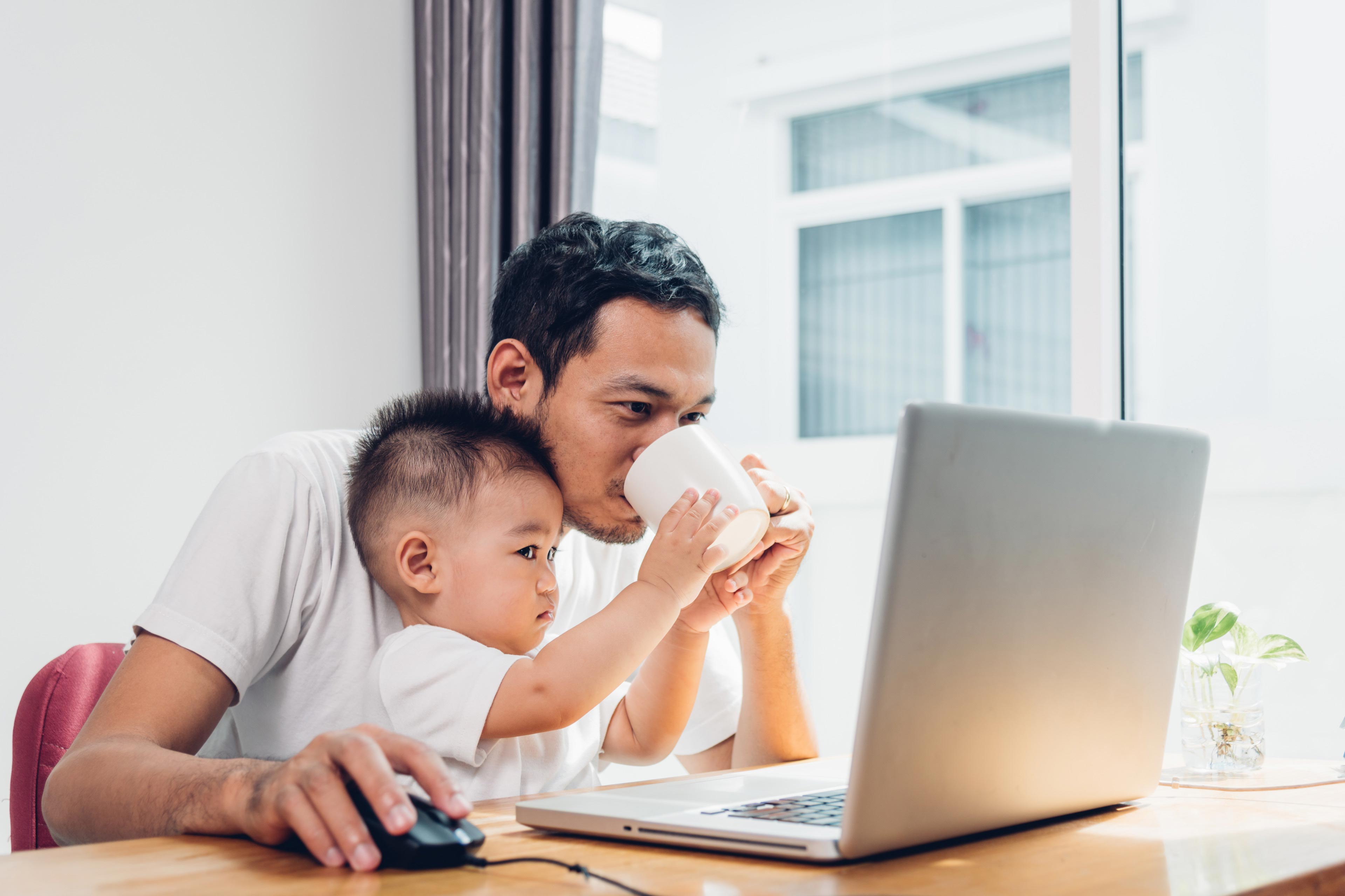 Father using working on laptop computer with son in home