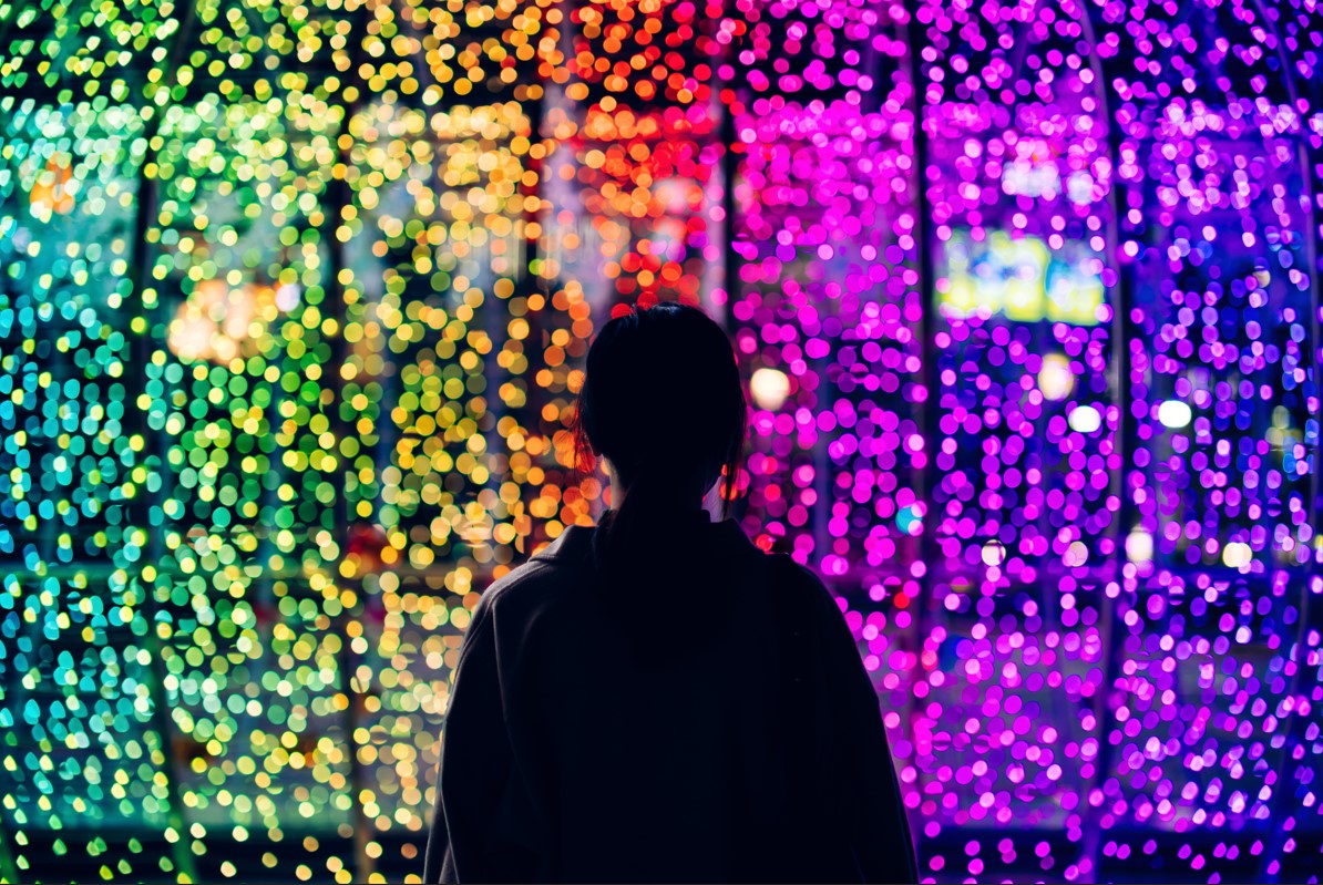 person looking at wall of rainbow colored lights