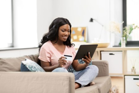 Happy woman with tablet pc and credit card at home