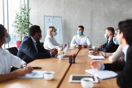 EY - People in face masks sitting during corporate meeting in office
