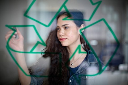 Young woman drawing recycling symbol on glass