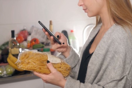 Women with phone voice recognition ai at home in kitchen