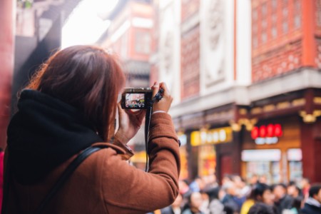 EY - Asian woman taking photo of busy street