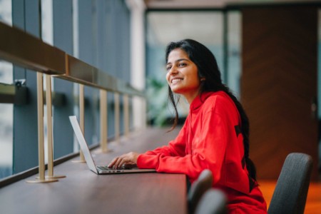 Youthful Indian woman looking away from her laptop