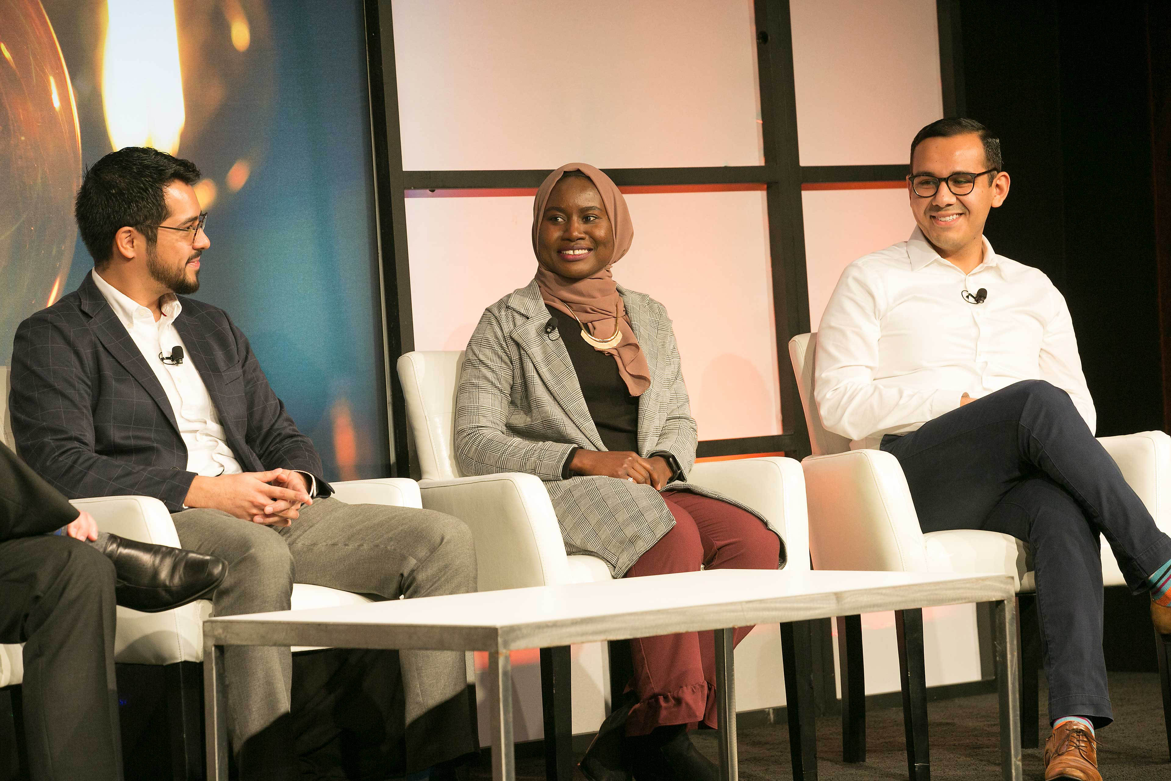 EY professionals Danny, Fatima and Francisco sit on a stage at an EY event.