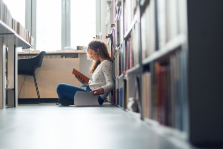 Girl sitting on floor of library studying
