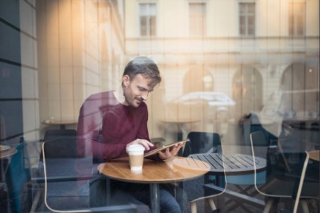 Window view of man using tablet in cafe