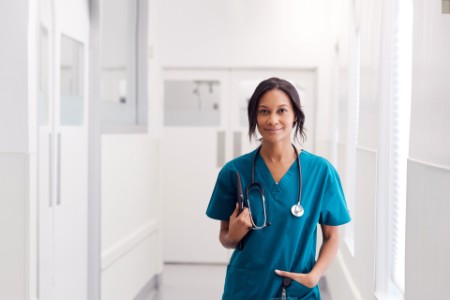 Doctor in scrubs holding tablet in hospital corridor 