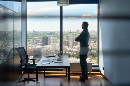 Silhouette of businessman standing in office with big city capital urban view