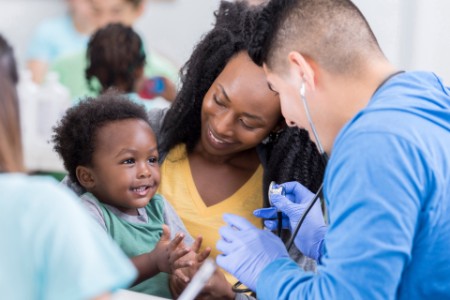 Adorable baby boy claps during medical exam