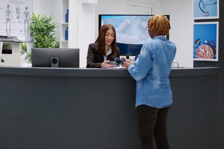 Female patient paying consultation with credit card at reception desk