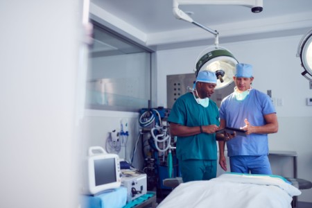 EY - Male surgeons wearing scrubs looking at digital tablet