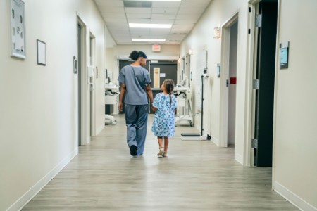 Nurse walking with girl in hospital corridor