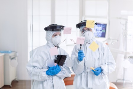 Professional dentists in ppe suit checking schedule