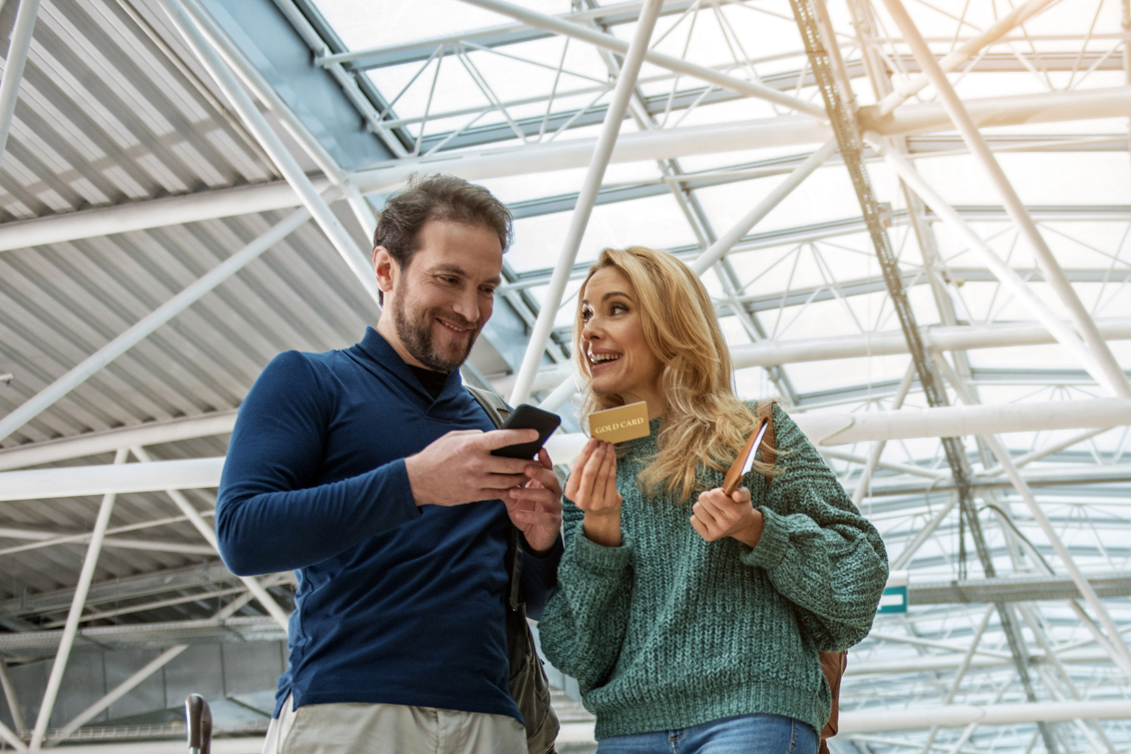 man and woman smiling, looking at a mobile phone