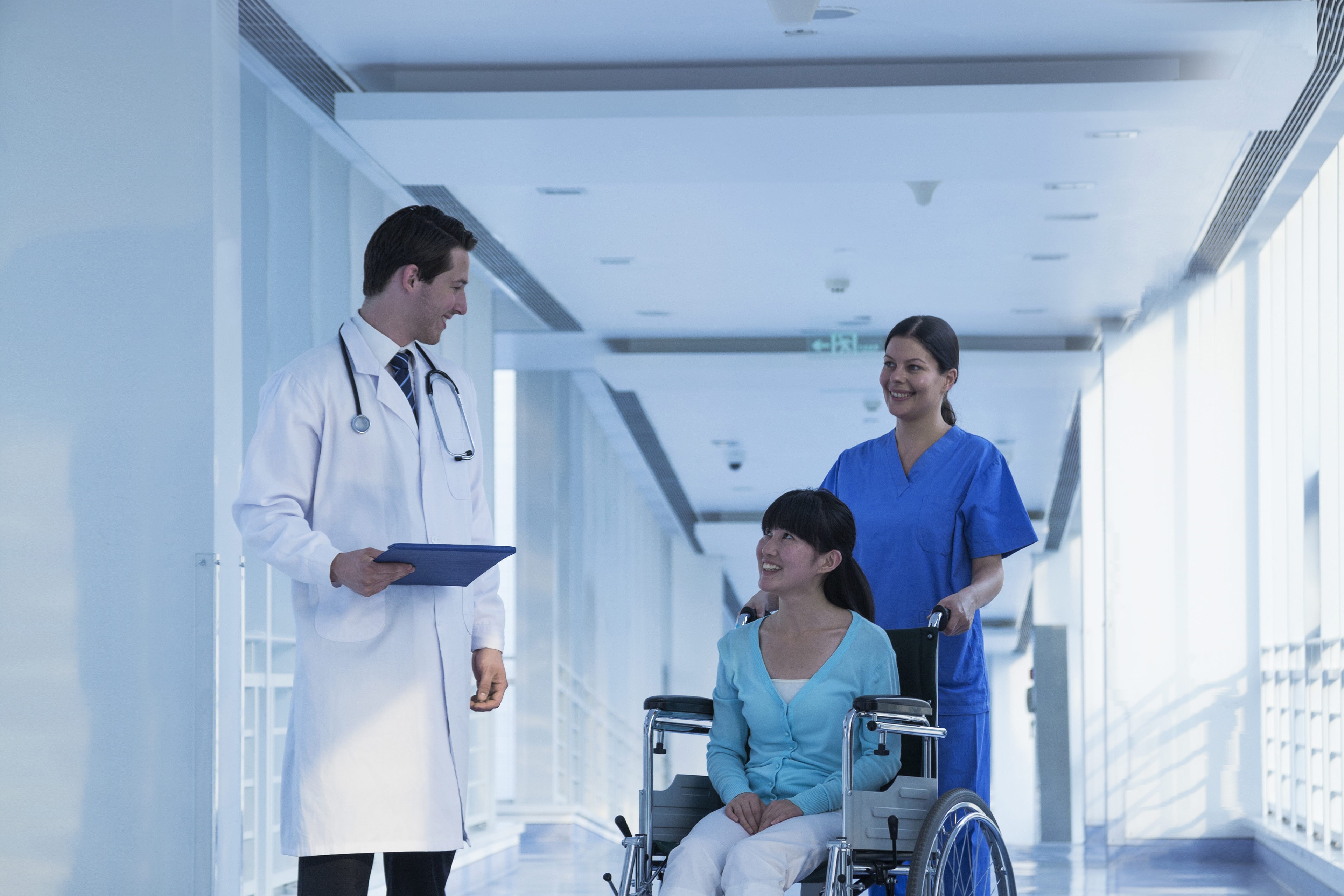 Nurse pushing patient in wheelchair talking to doctor