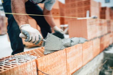 Worker using pan knife for building brick walls