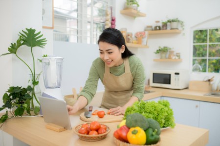 Woman cutting vegetables while pointing tablet