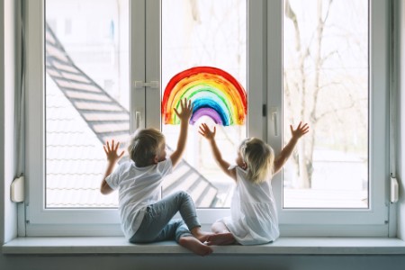 EY - Little-children-on-background-of-painting-rainbow-on-window