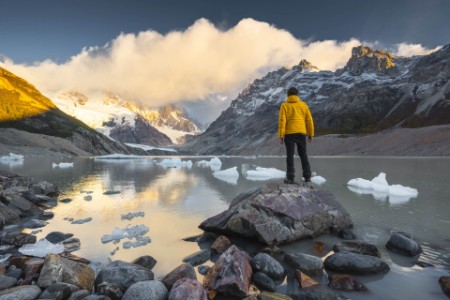 Foto de un hombre parado sobre una piedra observando el glaciar