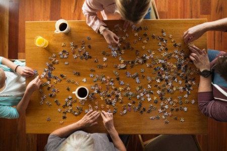 ey-assembling-jigsaw-puzzle-at-table