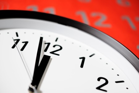 Close-up Clock face of deadline against large red calendar.